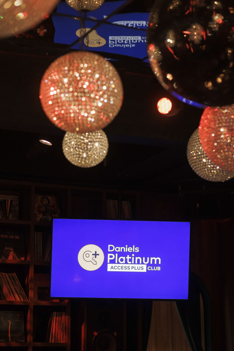 Glittering disco balls above "Daniels Platinum" club sign.