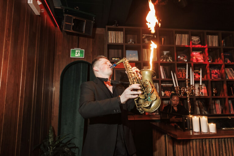 Musician playing saxophone with fire performance.