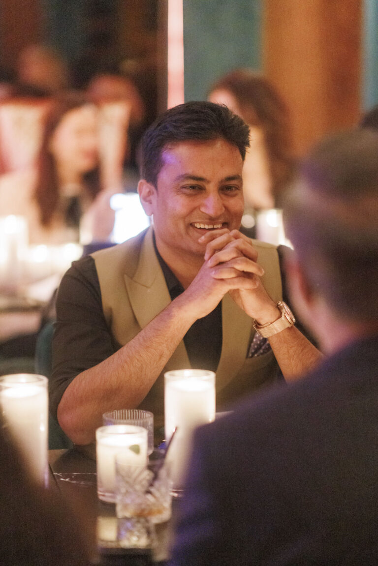 Man smiling at candlelit social gathering.