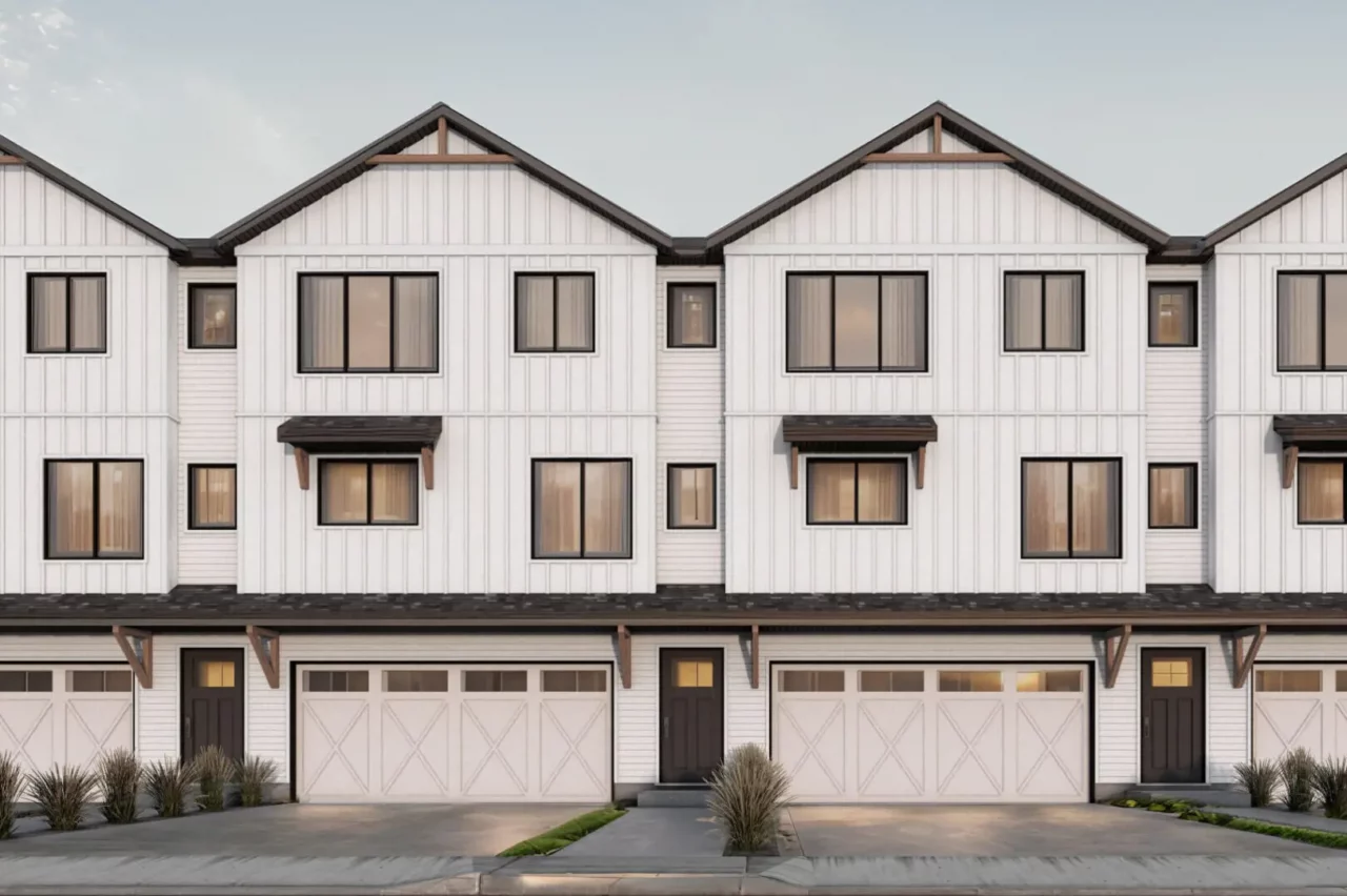 Modern white townhouse exterior with garage doors.